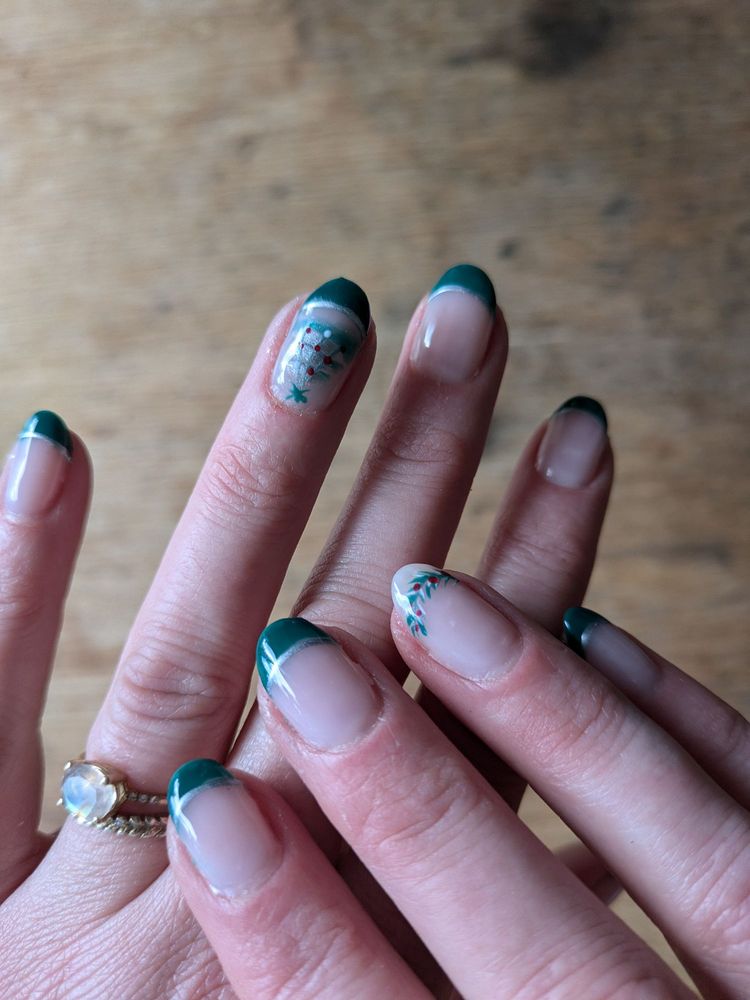 Full hand shot of green French manicure with delicate nail art at T Nails & Spa, Seattle